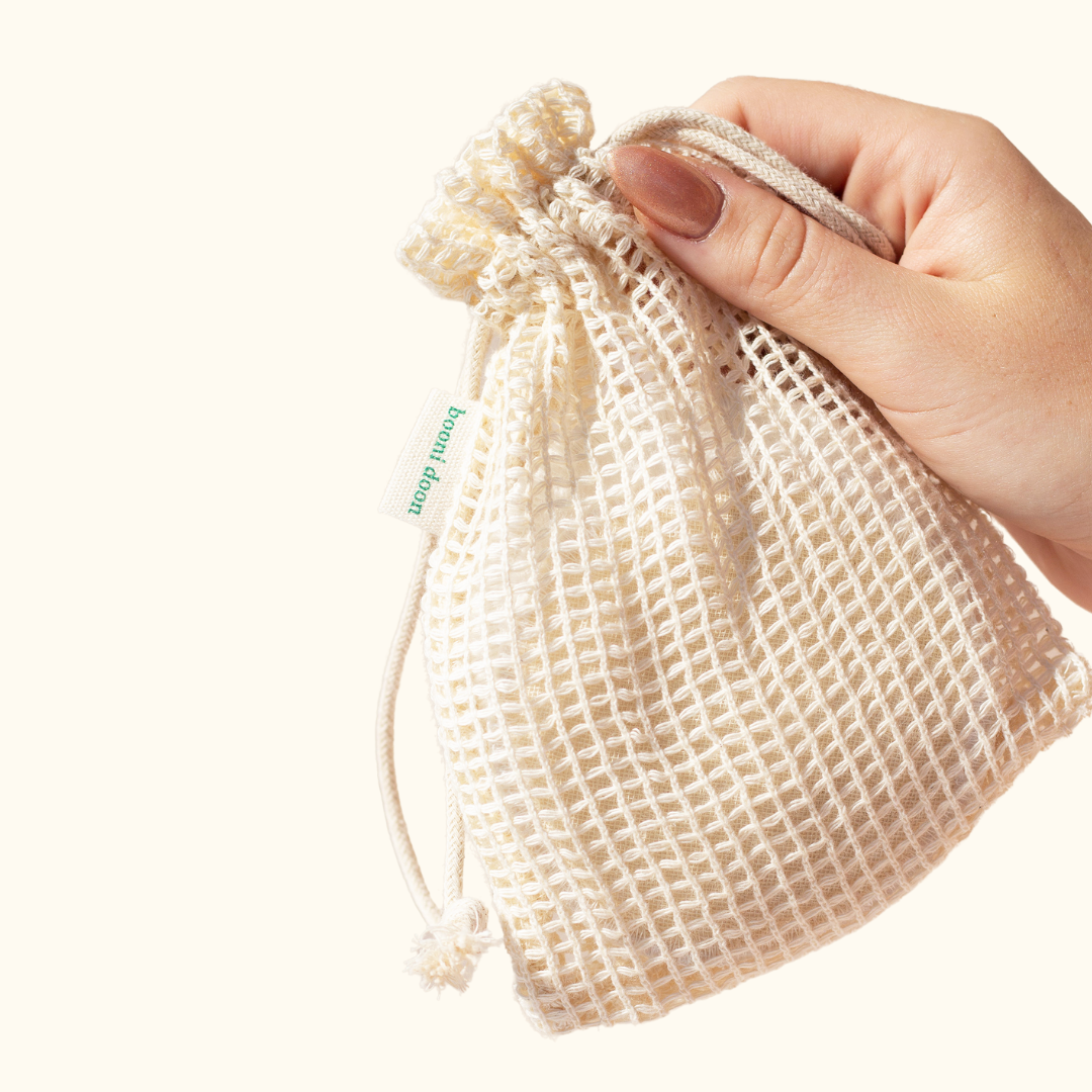 Image of woman's hand holding mesh bag containing booni doon's PLUSH reusable rounds